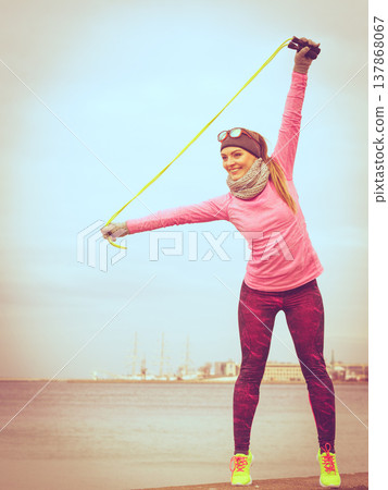 Woman training outdoor with jump rope on cold day Woman training outdoor with jump rope on cold day 137868067