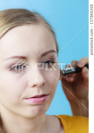 Makeup artist applying with brush rouge on female check 137868208