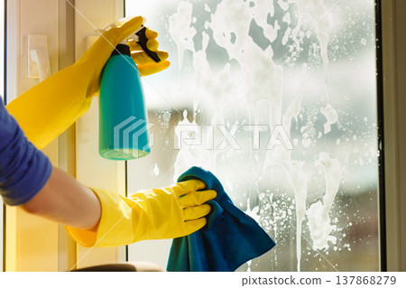 Hand cleaning window at home using detergent rag 137868279