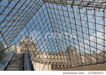 Interior of Louvre Pyramid with escalator and palace facade in Paris France Interior of Louvre Pyramid with escalator and palace facade in Paris France 137868453