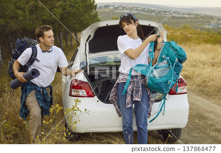 Couple with backpacks unloading car trunk before forest hike on quiet country road 137868477