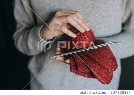 Female hands with hand knitted socks and yarn balls for knitting. 137868524