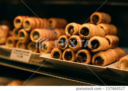 Sweet cannoli stuffed with chocolate and pistachio cream in a bakery. Sicilian dessert. 137868527