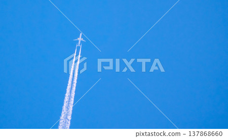 Airplane flying high in the sky leaving white trails during clear day with blue background 137868660