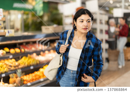 Woman in supermarket sales area looks into distance and searches for necessary goods Woman in supermarket sales area looks into distance and searches for necessary goods 137868864