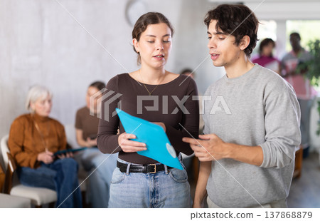 Female office worker discussing papers with guy Female office worker discussing papers with guy 137868879