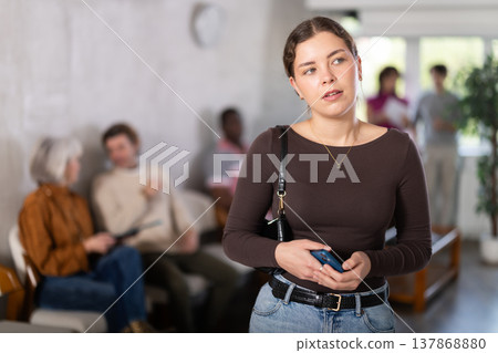 Woman holding mobile phone in waiting area in office Woman holding mobile phone in waiting area in office 137868880
