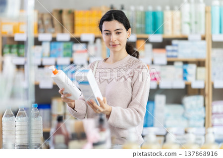 Young woman chooses cream at pharmacy Young woman chooses cream at pharmacy 137868916