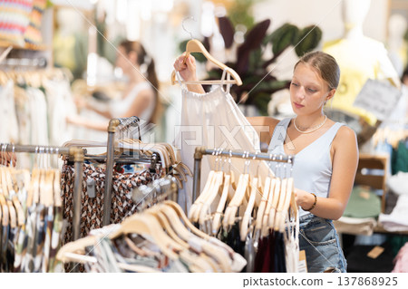 Girl customer chooses singlet blouse in branded store Girl customer chooses singlet blouse in branded store 137868925
