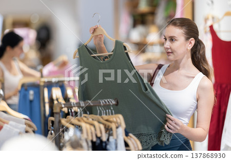 Girl customer chooses blouse in branded store Girl customer chooses blouse in branded store 137868930