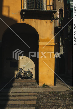 Motorcycle on a street of the old city Verona, Italy. Beautiful morning sunlight. Motorcycle on a street of the old city Verona, Italy. Beautiful morning sunlight. 137868952