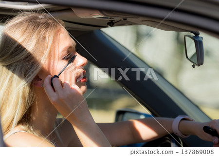 Woman applying mascara in car Woman applying mascara in car 137869008
