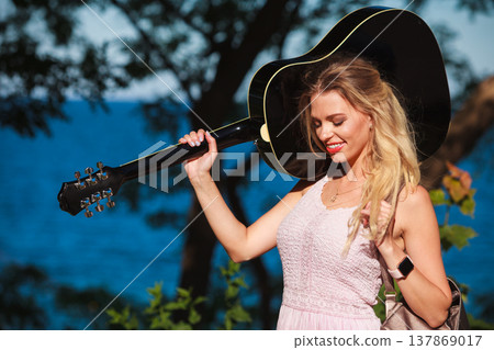 Blonde woman with acoustic guitar on seaside Blonde woman with acoustic guitar on seaside 137869017