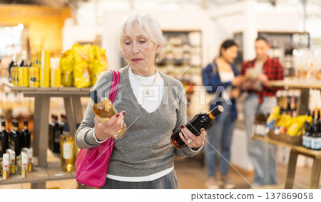 Elderly woman chooses wine at grocery store Elderly woman chooses wine at grocery store 137869058