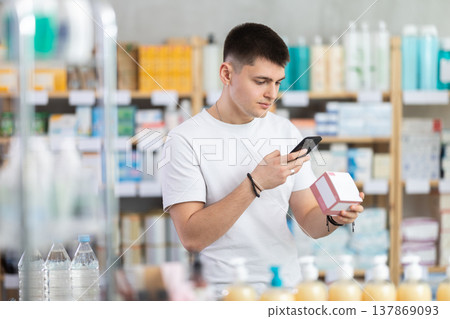Young man in pharmacy scans QR code on tablets box 137869093
