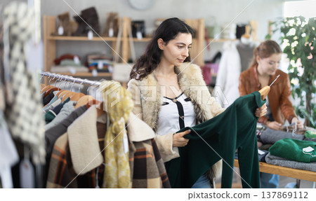 Armenian girl near showcase examine goods, buying warm dress. Armenian girl near showcase examine goods, buying warm dress. 137869112