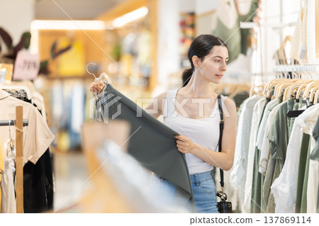 Young woman chooses pantalones in clothing store Young woman chooses pantalones in clothing store 137869114