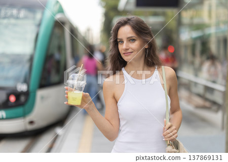 Young woman with glass of slush at subway station Young woman with glass of slush at subway station 137869131