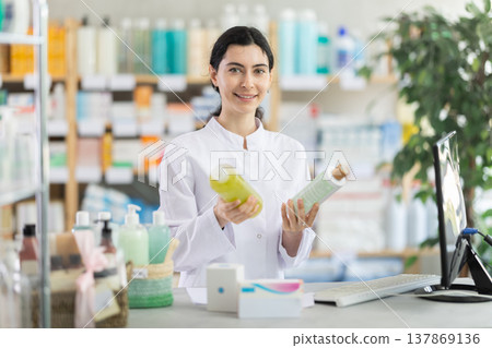 Young woman pharmacist offering shampoo or shower gel Young woman pharmacist offering shampoo or shower gel 137869136