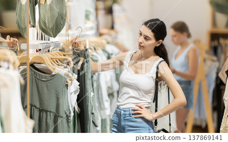 Girl customer chooses green trousers in branded store 137869141