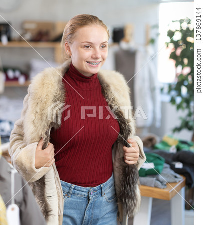 Girl try on fur coat in front of mirror Girl try on fur coat in front of mirror 137869144
