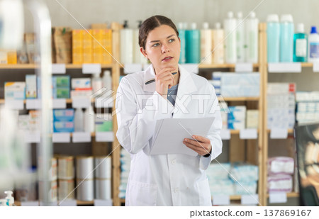 Young female pharmacist restocking using paper in drugstore Young female pharmacist restocking using paper in drugstore 137869167
