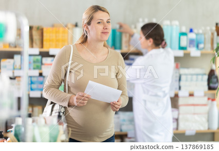 Pregnant woman chooses prescription pills at pharmacy 137869185