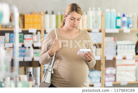 Pregnant woman chooses pills at pharmacy Pregnant woman chooses pills at pharmacy 137869189