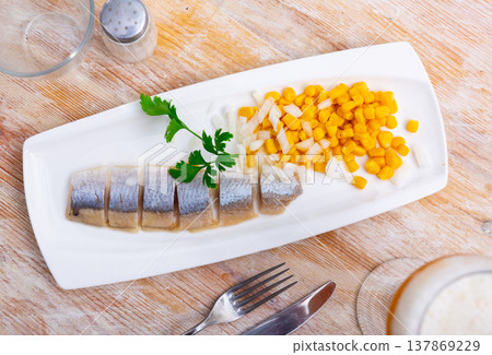 Sliced pickled herring fillet with corn and onions on plate Sliced pickled herring fillet with corn and onions on plate 137869229