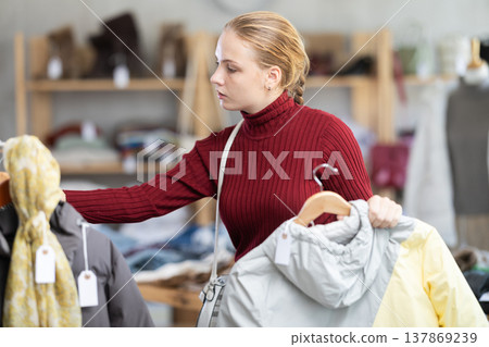 While shopping, teen girl browsing goods items and choose elect something warm outerwear in store While shopping, teen girl browsing goods items and choose elect something warm outerwear in store 137869239