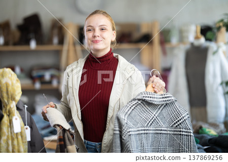 While shopping, teen girl browsing goods items and choose elect checkered coat in store While shopping, teen girl browsing goods items and choose elect checkered coat in store 137869256