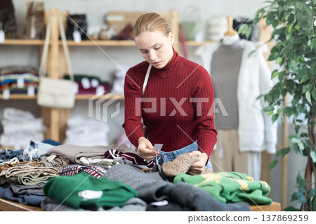 While shopping, teen girl browsing goods items and choose elect warm jumper in store While shopping, teen girl browsing goods items and choose elect warm jumper in store 137869259