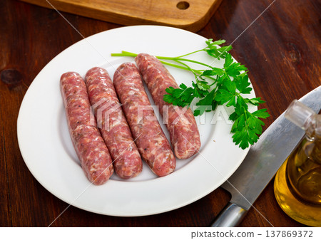 Fresh raw pork botifarra sausages ready for grilling on plate Fresh raw pork botifarra sausages ready for grilling on plate 137869372