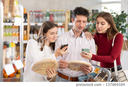 Family with teenage girl scanning QR on bottle of smoothie in supermarket Family with teenage girl scanning QR on bottle of smoothie in supermarket 137869384