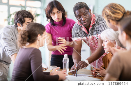 Men and women of different ages actively communicating at table 137869434