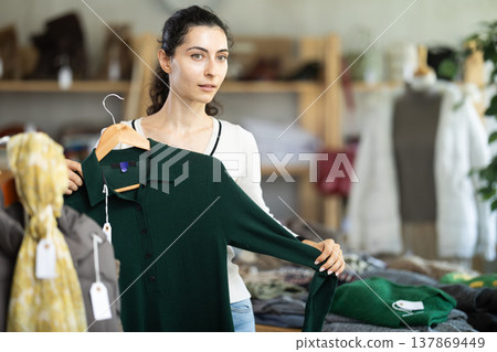 Armenian girl near showcase examine goods, buying warm dress. Armenian girl near showcase examine goods, buying warm dress. 137869449