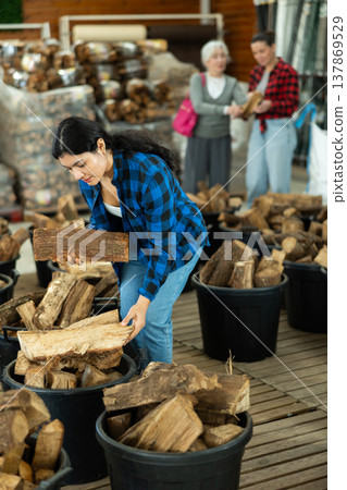Young woman buys bundle of firewood at hardware store Young woman buys bundle of firewood at hardware store 137869529
