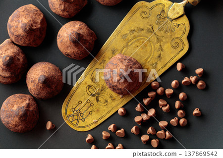 Chocolate truffles and vintage brass cake server on a black plate. Chocolate truffles and vintage brass cake server on a black plate. 137869542