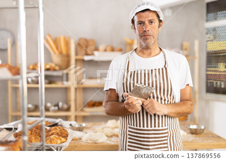 Adult male baker with dough scraper Adult male baker with dough scraper 137869556