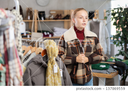 Selective teenage girl trying on winter coat in clothing store Selective teenage girl trying on winter coat in clothing store 137869559