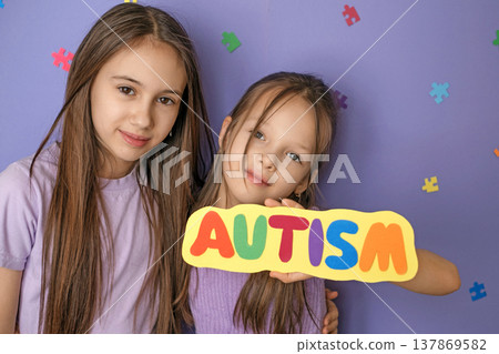 Cute, beautiful school-age girls are showing off a sign that says autism. Awareness and support for children with autism spectrum disorder 137869582