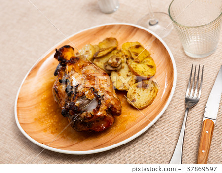 Pork knuckle baked in oven with boiled potatoes in white plate Pork knuckle baked in oven with boiled potatoes in white plate 137869597