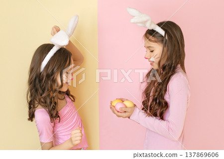 A girl gives Easter eggs to her cheerful sister, rejoicing at the holiday 137869606