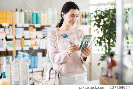 Female shopper chooses toothbrush in supermarket 137869634