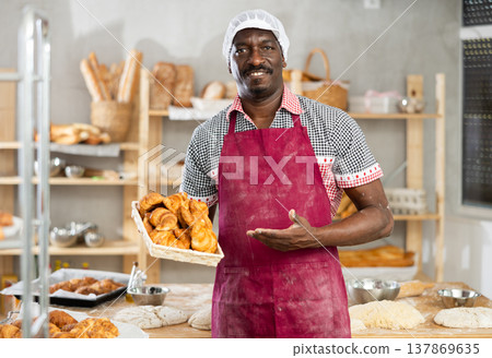 Successful black baker offering fresh croissants in bakery Successful black baker offering fresh croissants in bakery 137869635