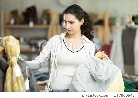 Armenian girl near showcase examine goods, buying something autumn outwear. 137869643