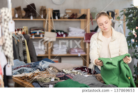 While shopping, teen girl browsing goods items and choose elect warm jumper in store While shopping, teen girl browsing goods items and choose elect warm jumper in store 137869653