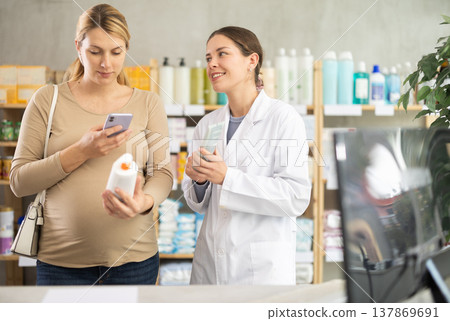 Pregnant woman in pharmacy scans QR code on antifungal cream, pharmacist offer similar product. 137869691