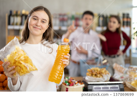 Teenage girl holding chips and juice in grocery store 137869699