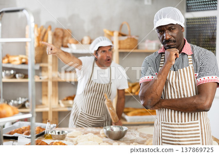 In bakery kitchen, confused African male employee during quarrel with man boss 137869725